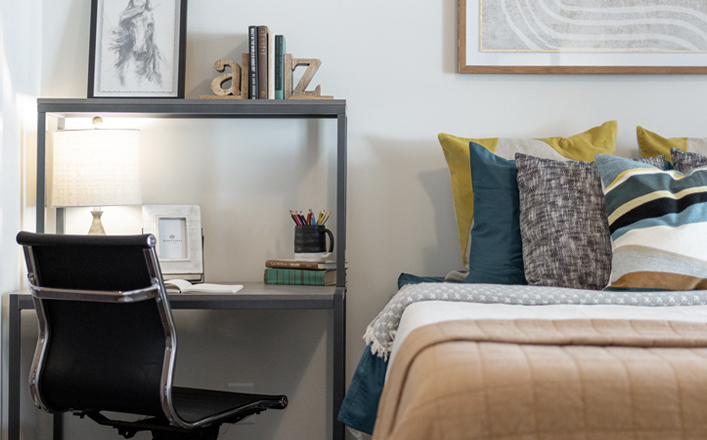 Desk next to bed with beige bed spread